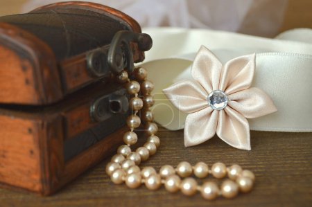 Photo for Pearl necklace, textile flower decoration and vintage chest - Royalty Free Image