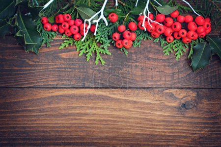 Téléchargez les photos : Décorations de Noël sur fond en bois avec espace de copie, baies rouges et brindilles vertes - en image libre de droit