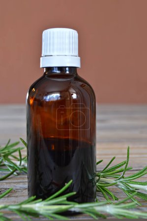 Foto de Botella con aceite esencial y ramitas de romero sobre fondo de madera - Imagen libre de derechos