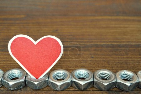 heart shape red sticker and hex nuts on wooden background