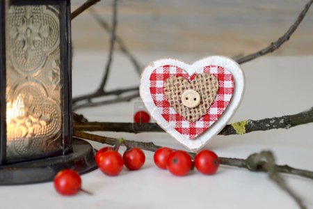 Photo for Christmas composition with vintage lantern, red viburnum berries, rustic wooden heart decoration and tree branch - Royalty Free Image