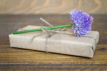 Foto de Caja de regalo decorada con flor silvestre púrpura sobre un fondo de madera - Imagen libre de derechos