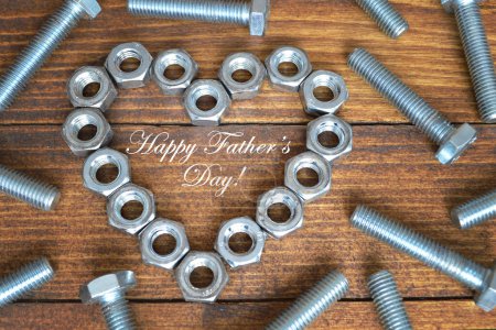 Téléchargez les photos : Happy father 's day card with metal screws and hex nuts on a wooden table. - en image libre de droit