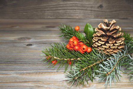 Foto de Composición navideña con cono de pino, bayas de serbal y rama de abeto sobre fondo de madera - Imagen libre de derechos