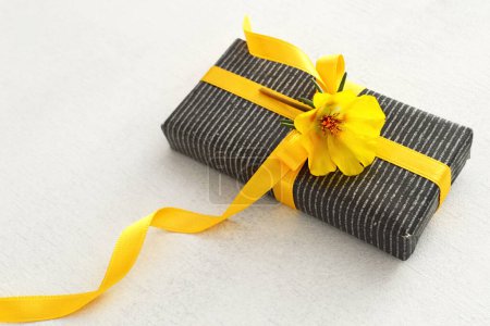 Téléchargez les photos : Coffret cadeau décoré avec ruban jaune et fleur sur fond blanc - en image libre de droit