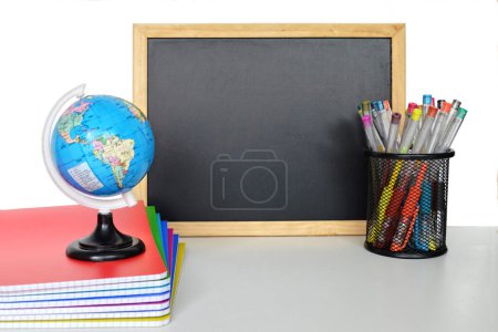 Photo for School blackboard with copybooks, globes and pens on white background - Royalty Free Image