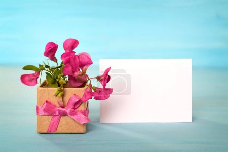 Foto de Tarjeta de felicitación vacía y flores silvestres rosadas arregladas en caja de regalo - Imagen libre de derechos
