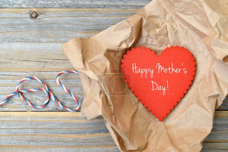 Téléchargez les photos : Carte de vœux de la fête des mères avec coeur rouge, papier d'emballage et ficelle sur fond en bois - en image libre de droit