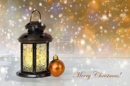 Foto de Feliz tarjeta de felicitación navideña. Linterna vintage con bola de Navidad naranja sobre fondo nevado - Imagen libre de derechos