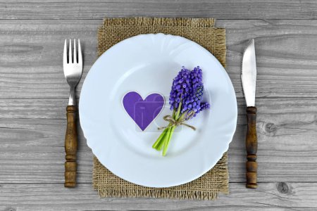 Foto de Día de la Madre ajuste de la mesa, plato blanco decorado con flores de muscari y corazón púrpura - Imagen libre de derechos