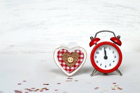 Téléchargez les photos : Réveil rouge et décoration coeur en bois rustique sur une table en bois blanc - en image libre de droit