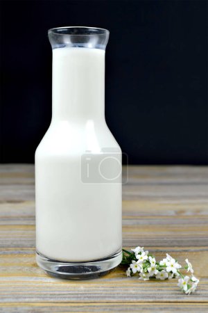 Téléchargez les photos : Bouteille de lait et fleurs blanches sur table en bois - en image libre de droit