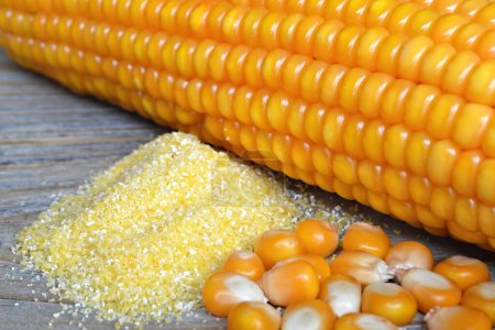 Foto de Granos de maíz crudos y harina de maíz sobre fondo de madera - Imagen libre de derechos