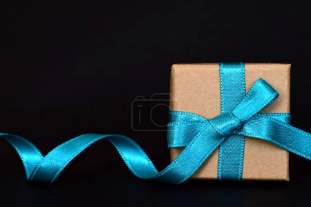 Foto de Gift box with blue ribbon on black background - Imagen libre de derechos