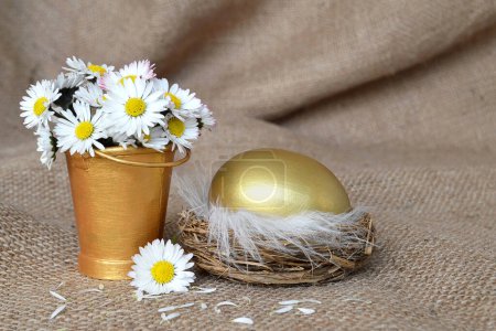 Téléchargez les photos : Œuf doré au nid et fleurs printanières sur toile de fond - en image libre de droit