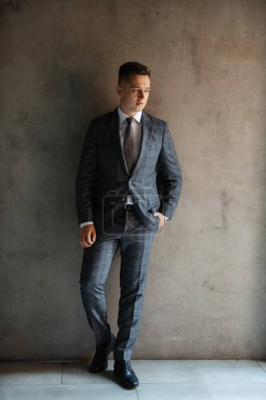 Photo for Portrait of a groom in a gray plaid suit with a tie on the wedding day in a bar - Royalty Free Image