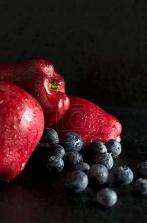 Téléchargez les photos : Belles pommes rouges avec des bleuets sur fond foncé vertical - en image libre de droit