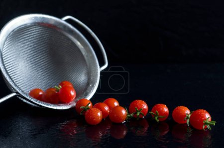 Photo for Baby Red Tomatoes with Stainless Steel Strainer on Black Background Horizontal - Royalty Free Image