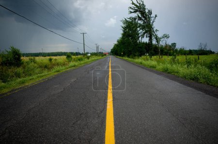 Photo for Country Road with Yellow Lane During a Summer Storm Horizontal - Royalty Free Image