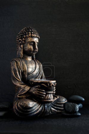 Photo for Bronze Gautama Buddha with Dark Rocks Isolated on Black Vertical - Royalty Free Image
