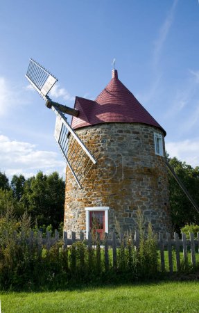 Foto de Hermoso molino de viento con cerca de madera antigua en L 'Isle-aux-Coudres Quebec Vertical - Imagen libre de derechos