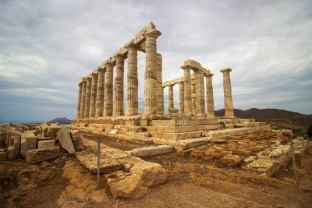 Les ruines d'un temple grec antique intemporel sont hautes, entourées de colonnes, sous un ciel dramatique et nuageux