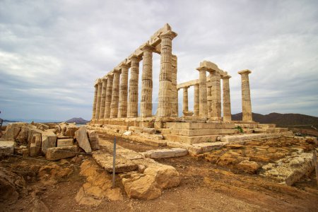 Ruines majestueuses de l'ancien temple de Poséidon au cap Sounion sous un ciel nuageux surplombant la mer Égée. Photo de haute qualité
