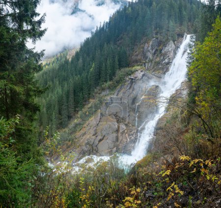 Foto de Krimml Waterfalls, Krimmler Wasserfalle, en el Parque Nacional High Tauern, Austria. El río Krimmler Ache cae. Hermosa cascada dramática en un día lluvioso brumoso. Senderismo en los Alpes austríacos - Imagen libre de derechos