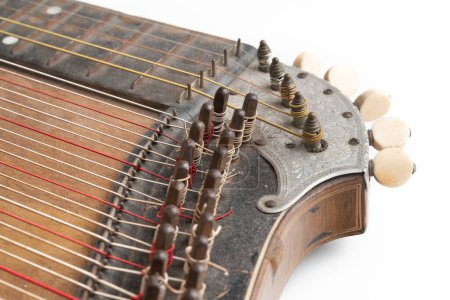 Foto de High angle studio shot of vintage, old wooden zither isolated on white background. Detail of zither mechanics and tuning pins. Dusty and scratched musical instrument - Imagen libre de derechos