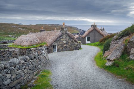 Téléchargez les photos : Garenin, Écosse - 08.25.2016 : Vieilles maisons en pierre de Gearrannan Blackhouse Village par une journée nuageuse typique . - en image libre de droit