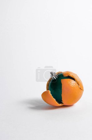 Photo for Conceptual green bauble inside of an orange on white background. New year decoration composition with copy space. - Royalty Free Image