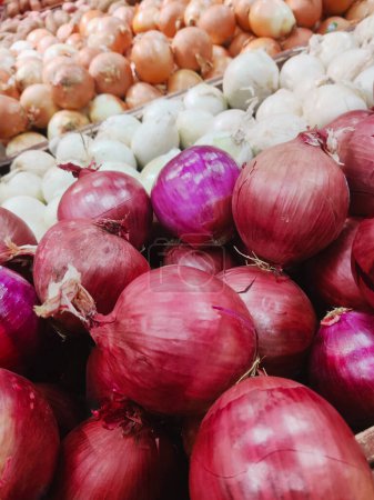 Onion vegetables in fresh produce section of grocery store or farmers market. Organic red, yellow, white, sweet onions. Buying and selling vegetables. Healthy food shopping. Vegetarian or vegan diet