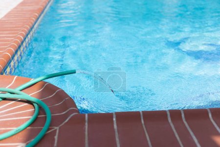 Téléchargez les photos : Tuyau d'eau remplissant la piscine, gros plan. Entretien piscine - en image libre de droit