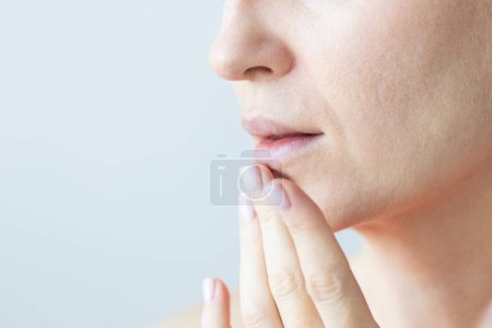 Una mujer tocándose suavemente los labios. Mujer con arrugas nasolabiales, problema de piel seca y con grandes poros en la cara. Nutrición de la piel