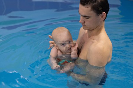 Erste Erfahrungen mit Wasser. Baby knallt nervös mit den Fingerknöcheln im Wasser. 