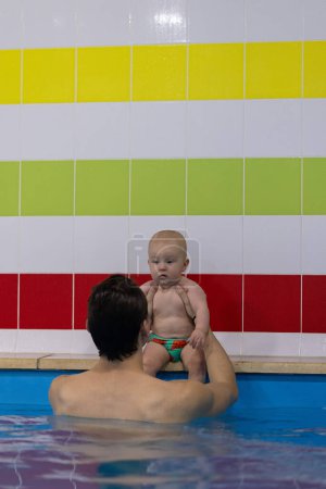 Curioso bebé escuchando el entrenador de natación y preparándose para saltar al agua. Clases de natación 