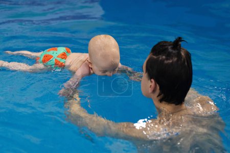 Baby trying to dive under water. Baby drinking water of swimming pool. Disinfection and cleaning of swimming pool. 