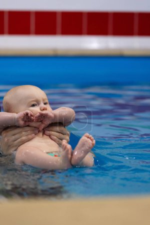 Erste Erfahrungen mit Wasser. Baby knallt nervös mit den Fingerknöcheln im Wasser. 