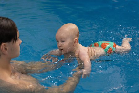 Neugeborenes hat Schwimmunterricht im Schwimmbad mit Schwimmtrainer