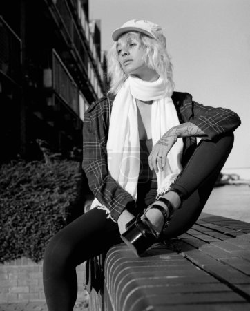 Téléchargez les photos : An alternative female model is sitting on stairs outside in a sunny day. Portrait made with an medium format analog film camera. Monochrome. - en image libre de droit