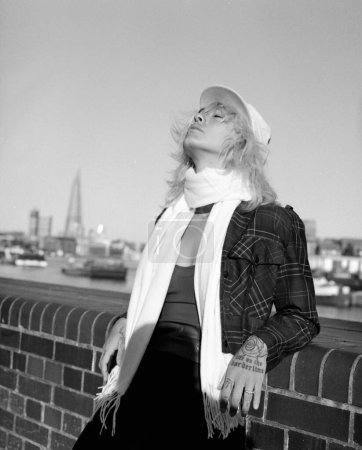 Téléchargez les photos : Analog portrait of relaxed female model posing beside Thames River. Portrait made with medium format film camera. Monochrome. - en image libre de droit