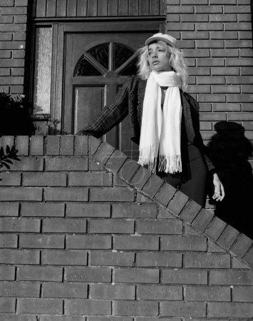 Téléchargez les photos : An alternative woman is standing on stairs under harsh light. Image made with medium format analog film camera. Monochrome. - en image libre de droit