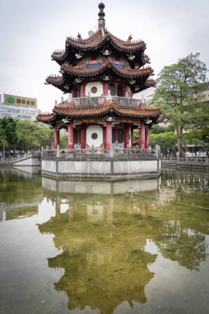Photo for Small Asian temple in city park reflected in a pond, vertical shot, Taipei, Taiwan. - Royalty Free Image