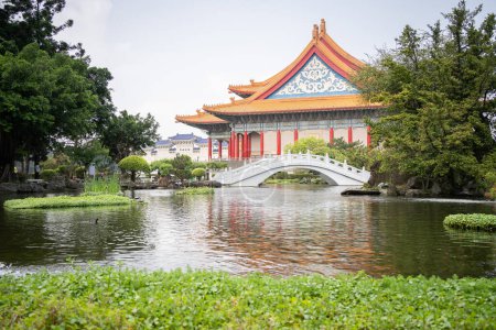 Beautiful Asian garden with bonsais, pond with bridge and majestic temple in background, wide,Taiwan.