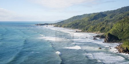 Foto de Costa exótica áspera con agua azul del océano, grandes olas y vegetación de la selva tropical, Nueva Zelanda. - Imagen libre de derechos