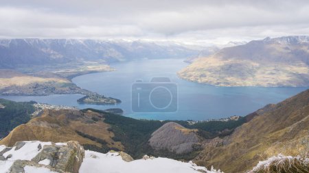 View on township, alpine lake and surrounding mountains from peak summit in New Zealand.