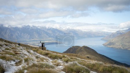 Alpine landscape with mountains, lake and toilet for hikers, New Zealand.