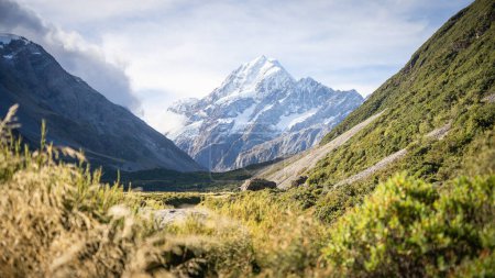 Massive snowy mountain with glacier towering above scenic alpine valley, Mt Cook, New Zealand.