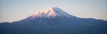 Panoramic shot of massive standalone mountain with snow cap during colorful sunset, Eastern Turkey.