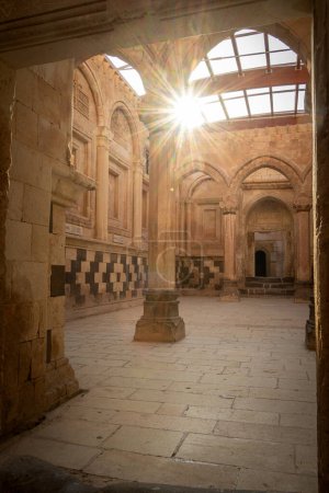 Vertikale Aufnahme der Sonne, die durch das historische arabische Palastinnere mit Bögen und Säulen scheint.